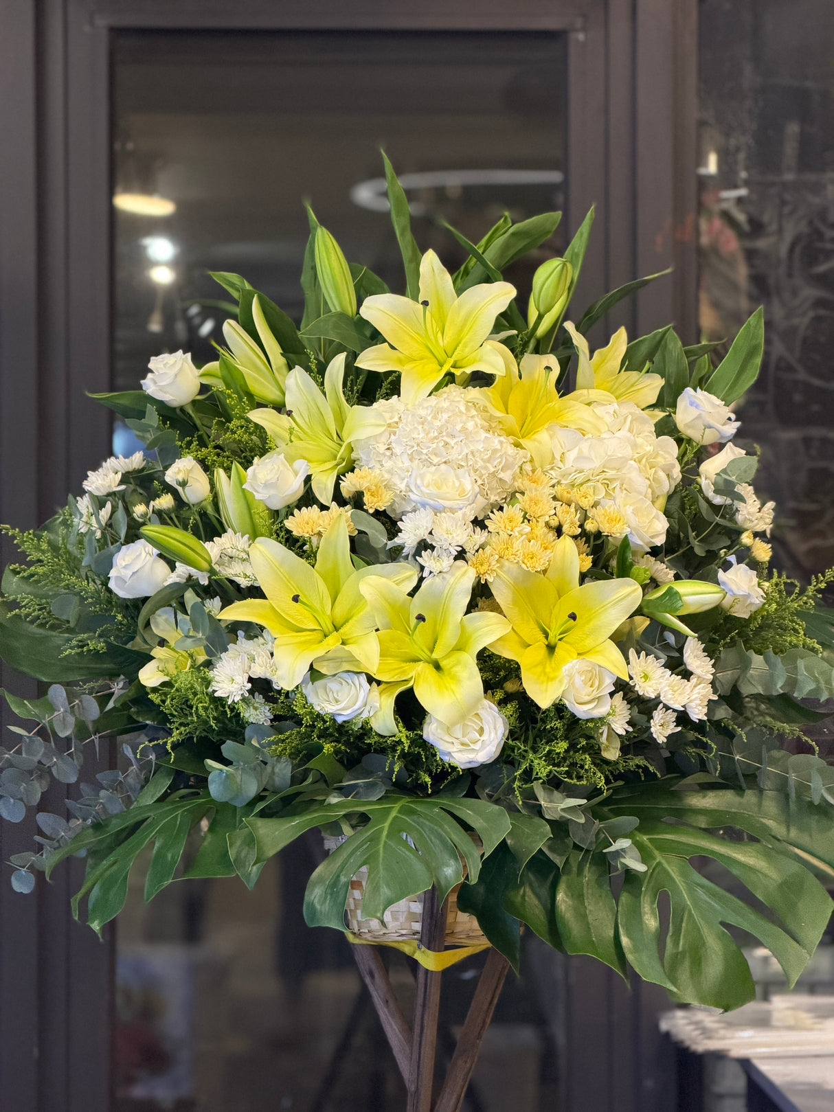 花點時間 Reflower 浩氣長存黃百合與白繡球素雅帛事花牌,特別配搭冰清玉潔的冰藍玫瑰、菊花與龜背葉,配色莊重溫暖,適合送往殯儀館及教會表達哀悼。