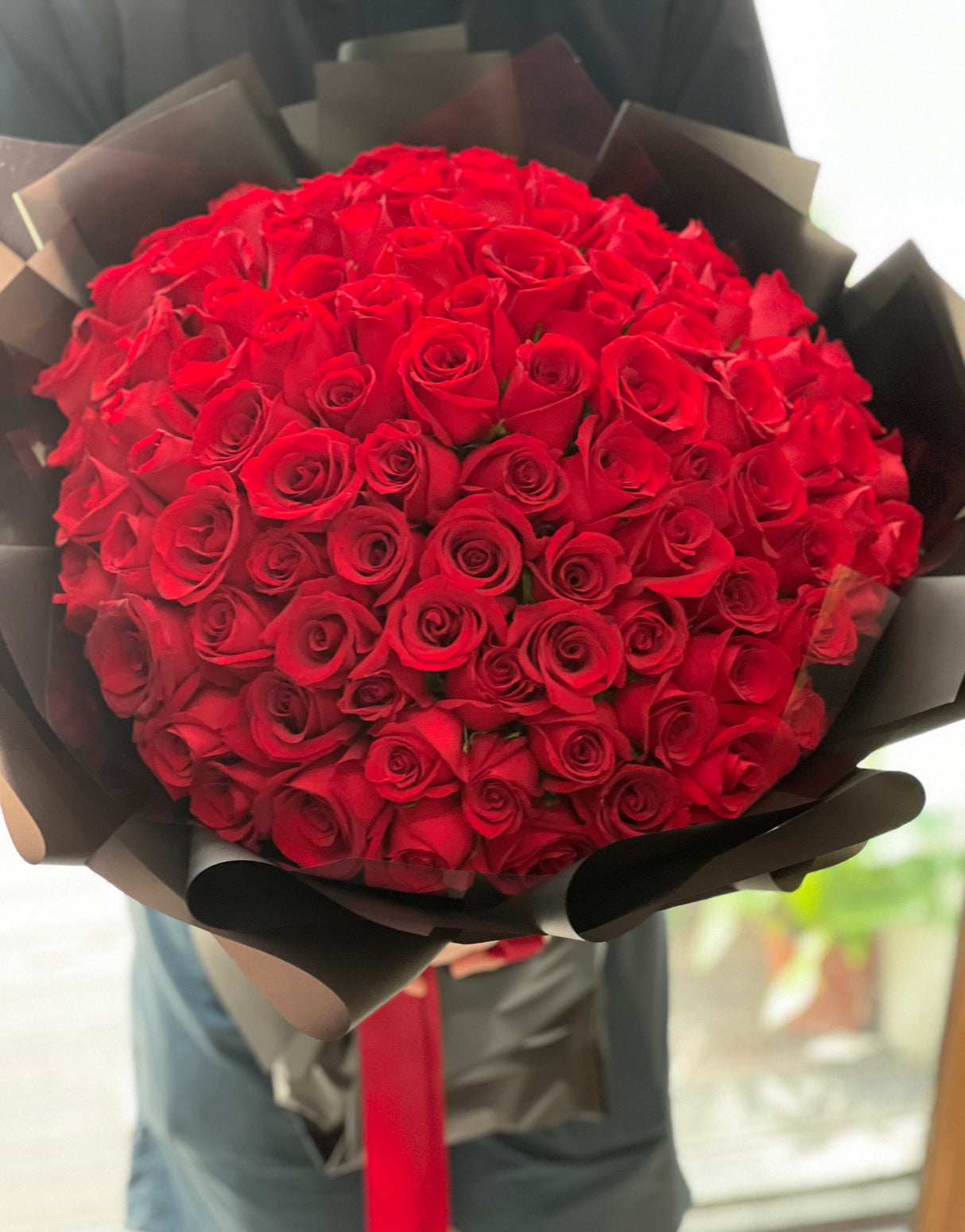 Reflower HK ultimate proposal bouquet featuring 99 premium red roses, strikingly wrapped in modern matte black paper with a red ribbon for a luxurious contrast.