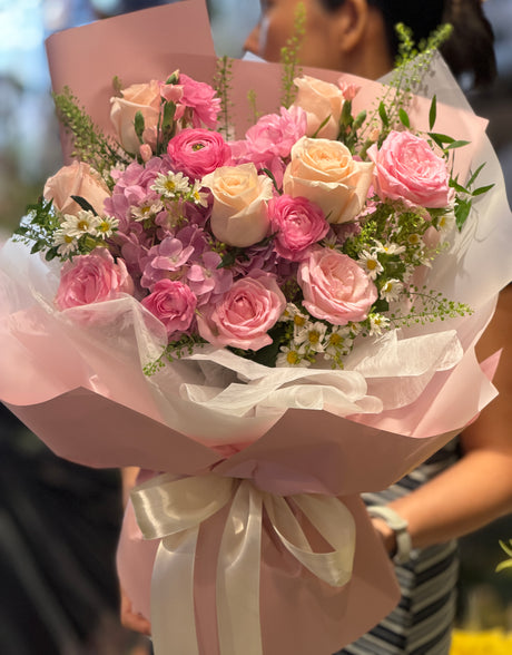 花點時間 Reflower 甜美浪漫花束，包含香檳玫瑰、粉紅玫瑰、粉色小牡丹與白色洋甘菊，採用霧面粉色包裝紙與白色波浪雪紗及白絲帶，適合女朋友生日及紀念日送花。