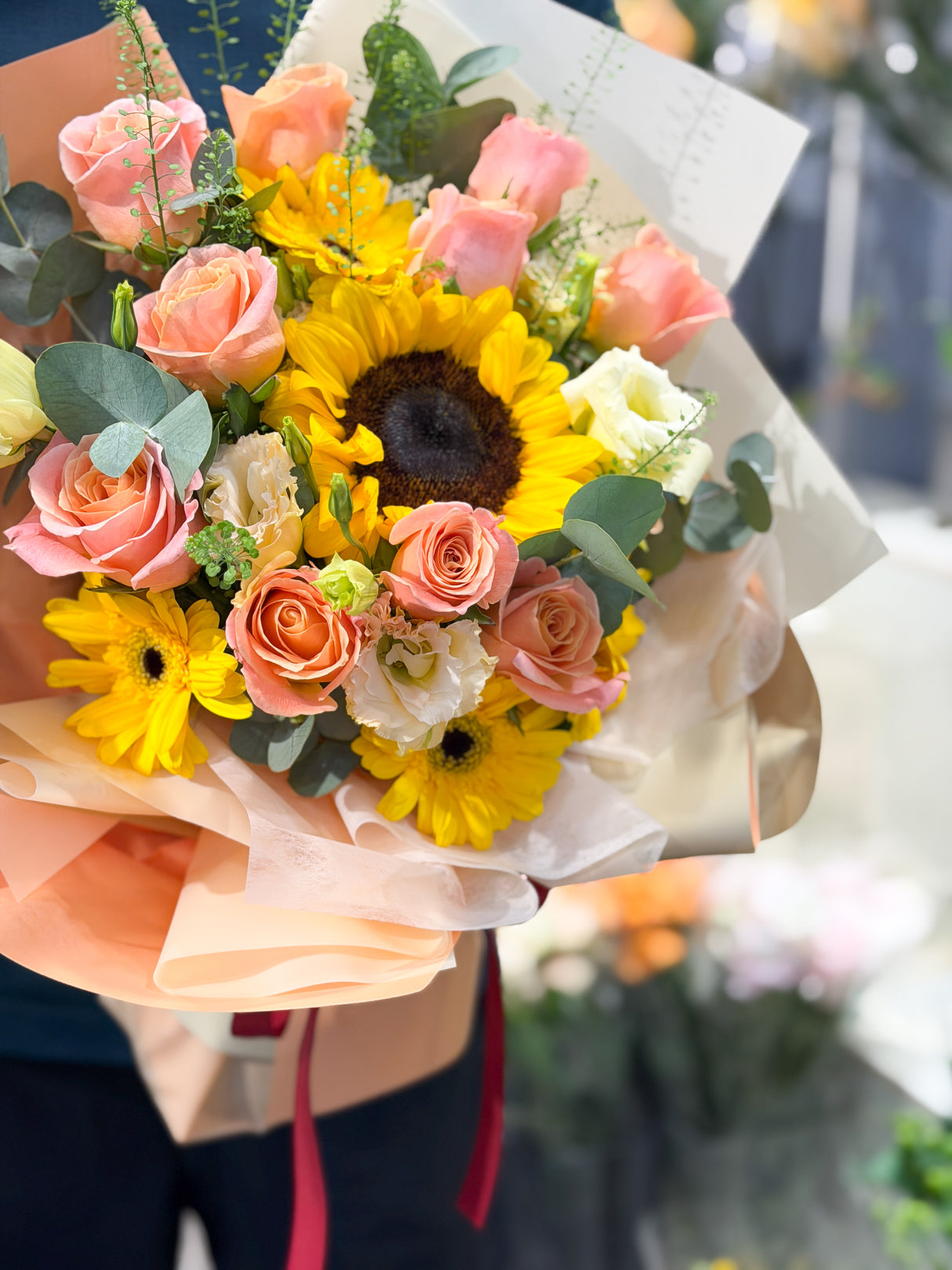 Reflower HK vibrant graduation bouquet featuring a bright sunflower, peach roses, and yellow gerberas, wrapped in warm peach paper, perfect for graduation photos and ceremonies.