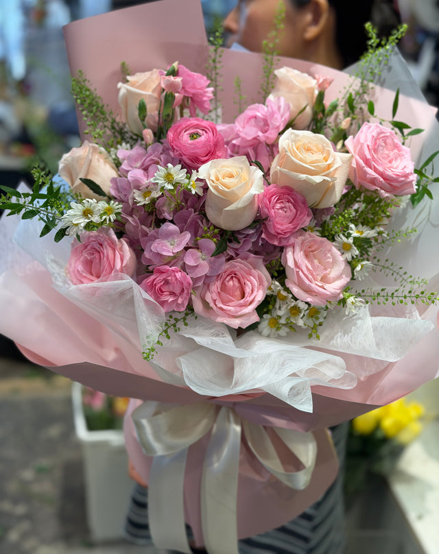 花點時間 Reflower 甜美浪漫花束，包含香檳玫瑰、粉紅玫瑰、粉色小牡丹與白色洋甘菊，採用霧面粉色包裝紙與白色波浪雪紗及白絲帶，適合女朋友生日及紀念日送花。