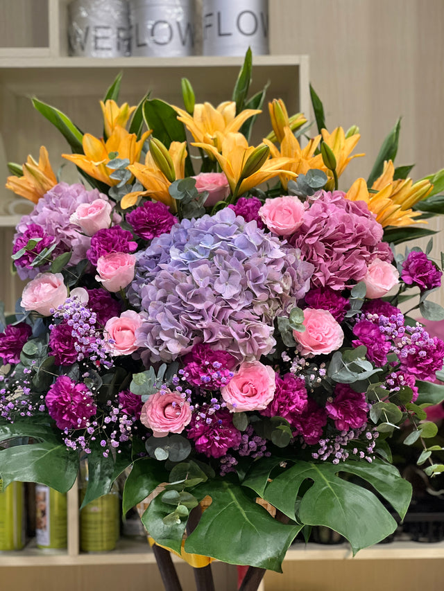 花點時間 Reflower 鴻圖大展粉紅百合配紅太陽菊開張花籃，底襯大型翠綠龜背葉，大氣豐滿，適合新店開張及寫字樓喬遷祝賀。