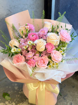 Reflower HK sweet and romantic bouquet featuring champagne roses, pink roses, pink ranunculus, and chamomile, elegantly wrapped in matte pink paper and wavy white organza with a white ribbon.