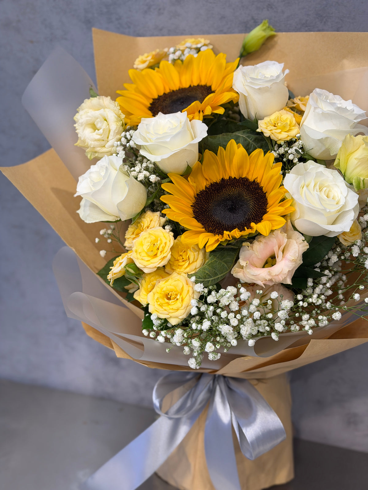 Reflower HK gender-neutral graduation bouquet featuring sunflowers, white roses, and eustoma, wrapped in hipster kraft paper, perfect for male and female graduates.