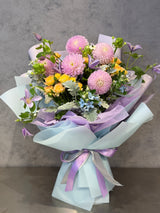 Reflower HK dreamy pastel bouquet featuring pink pompon dahlias, yellow spray roses, and light purple clematis, beautifully wrapped in light blue and lavender paper.