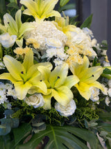 Reflower HK elegant sympathy flower stand featuring yellow lilies, a white hydrangea, ice blue roses, and chrysanthemums, designed for funeral homes and memorial services to express deepest condolences.