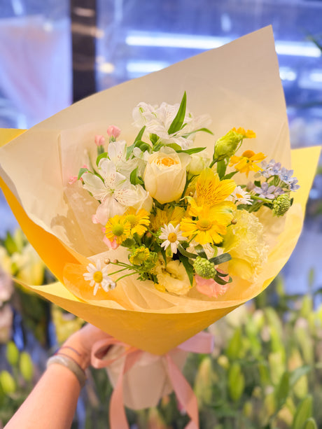 花點時間 Reflower 清新淡黃玫瑰、黃白百合水仙與洋甘菊混合花束，採用明黃色與白色霧面包裝，配上粉色絲帶，充滿陽光氣息。