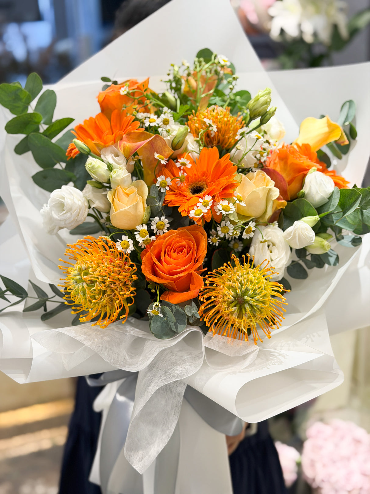 花點時間 Reflower 活力晨曦橙色針墊花與橙玫瑰花束，配搭太陽菊、洋甘菊及純白包裝，充滿陽光正能量，為畢業及升職送花首選。