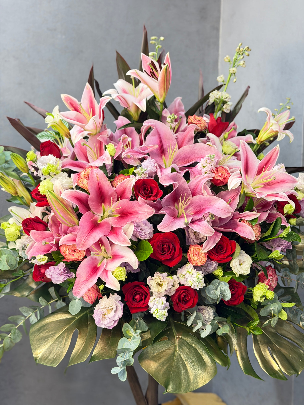 花點時間 Reflower 金玉滿堂粉百合與紅玫瑰開張花籃，配搭蜜桃色小牡丹與底部金漆龜背葉，色彩濃烈喜慶，祝賀新店開張生意興隆、財源滾滾。
