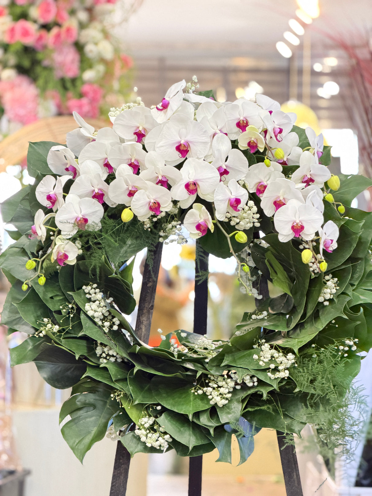 Reflower HK elegant Western sympathy wreath featuring premium white Phalaenopsis orchids, monstera leaves, and baby's breath, designed for funeral homes and memorial services to express deepest condolences.