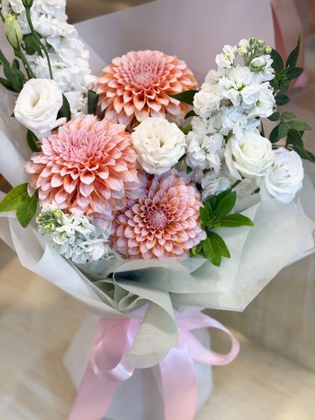 Reflower HK elegant and fresh bouquet featuring peach pompon dahlias, white stock, and white roses, wrapped in ethereal white and mint frosted paper.