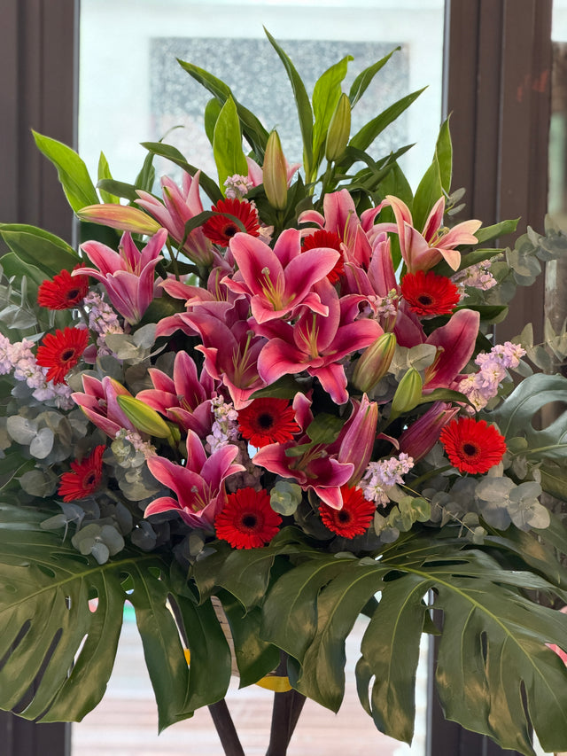 花點時間 Reflower 鴻圖大展粉紅百合配紅太陽菊開張花籃，底襯大型翠綠龜背葉，大氣豐滿，適合新店開張及寫字樓喬遷祝賀。