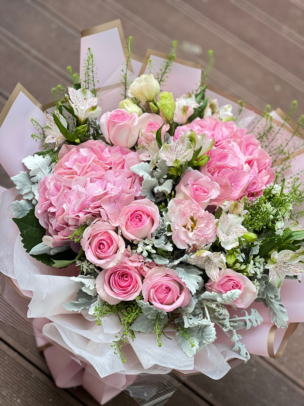 Reflower HK dreamy romantic bouquet featuring a pink hydrangea, pink roses, and Dusty Miller, luxuriously wrapped in Korean-style gold-edged pink paper and wavy organza.