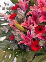 Reflower HK grand opening flower stand featuring large pink lilies, vibrant red gerberas, and large monstera leaves, perfect for business openings and congratulatory events.