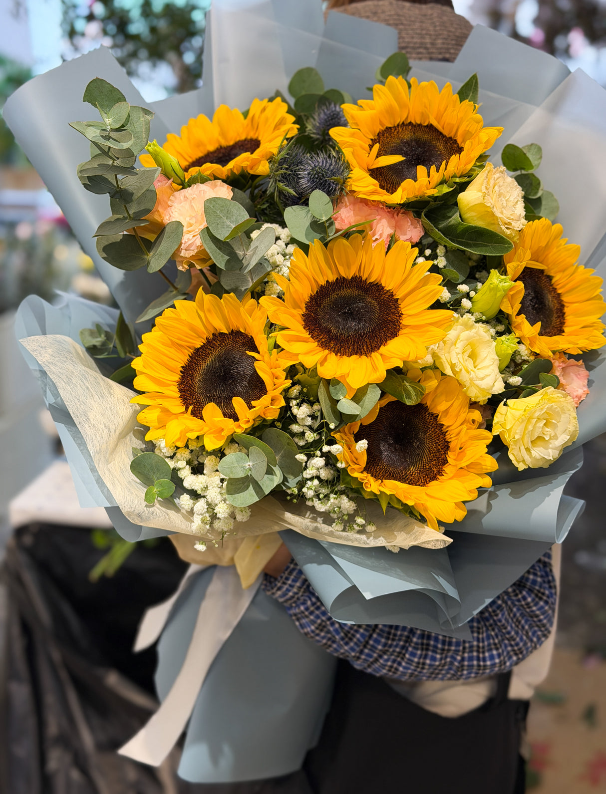 Reflower HK vibrant bouquet featuring yellow sunflowers, blue eryngium, and baby's breath, wrapped in elegant grey-blue paper, perfect for graduations and gifts for him.