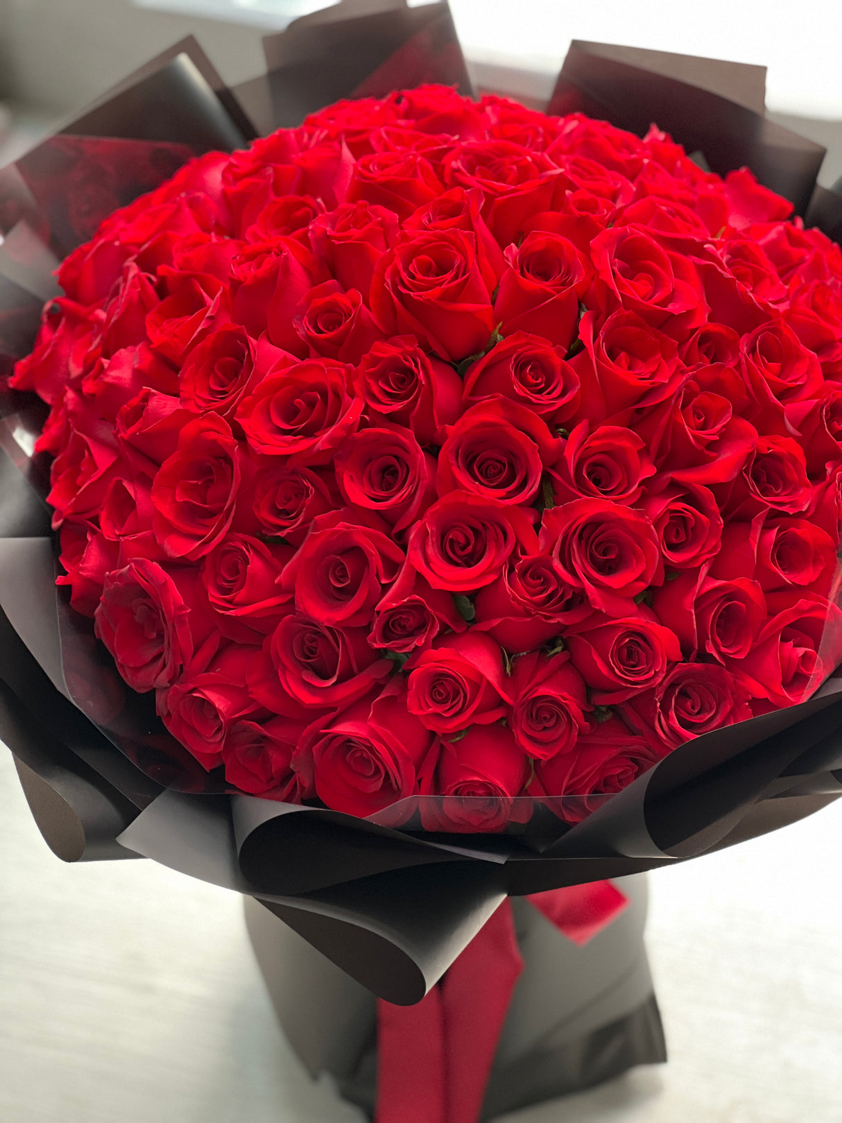 花點時間 Reflower 永恆摯愛 99 枝頂級紅玫瑰求婚巨型花束，採用極具現代奢華感的純黑霧面包裝與紅色絲帶，強烈對比展現霸道深情。