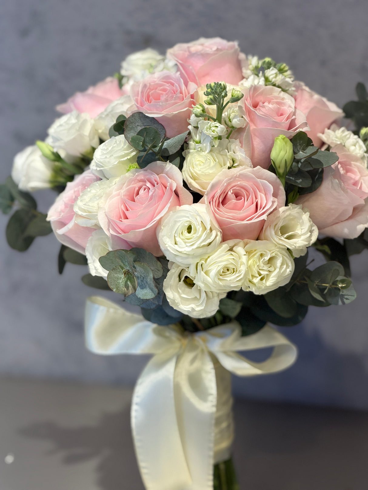 Reflower HK elegant bridal bouquet featuring soft pink roses, white eustoma, and eucalyptus leaves tied with a silk ribbon.